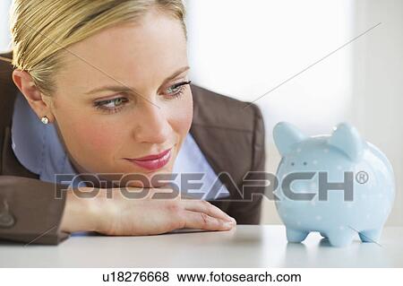 Businesswoman looking at piggy bank View Large Photo Image Stock Photo - Businesswoman looking at piggy bank. Fotosearch