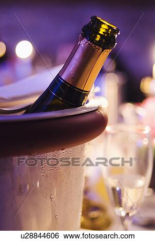 Stock Photograph - Champagne bottle cooling in ice bucket. Fotosearch