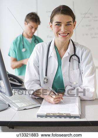 Cheerful female doctor with surgeon in background View Large Photo Image Stock Image - Cheerful female doctor with surgeon in background. Fotosearch