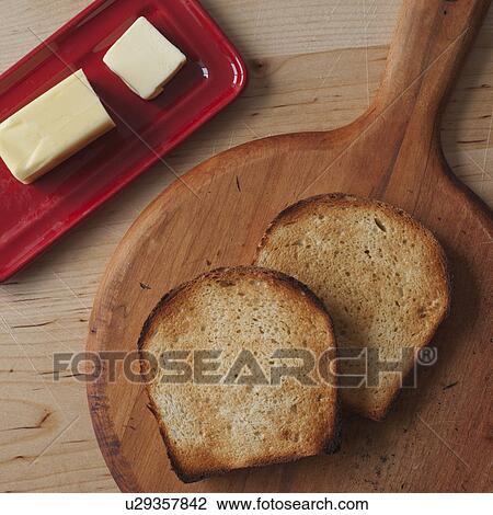 Stock Image - Close up of butter and toasted bread slices on cutting board . Fotosearch