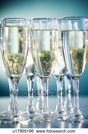 Stock Photograph - Close up of champagne flutes on blue background. Fotosearch
