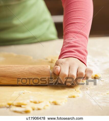 Stock Photo - Close-up of girl (6-7) rolling dough. Fotosearch