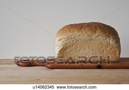 Stock Photography - Close up of loaf of bread on cutting board. Fotosearch