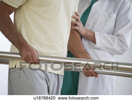 Stock Image - Close-up of physiotherapist assisting patient with recovery exercise. Fotosearch