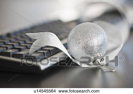 Picture - Close-up of silver bauble and computer keyboard. Fotosearch