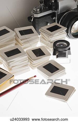 Stock Image - Close up of slides and camera on light box. Fotosearch