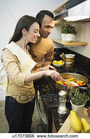 Stock Photograph - Couple cooking meal in kitchen. Fotosearch