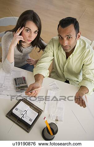 Stock Photograph - Couple doing taxes and looking at camera. Fotosearch