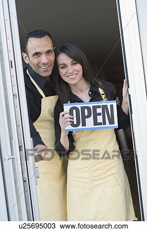 Stock Image - Couple holding open sign. Fotosearch