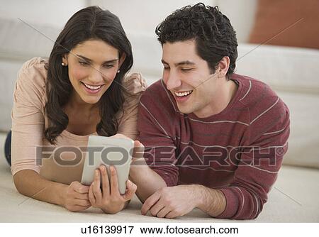 Couple lying on floor using palmtop View Large Photo Image Stock Photo - Couple lying on floor using palmtop. Fotosearch