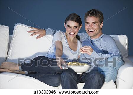 Couple sitting in front of television View Large Photo Image Stock Photograph - Couple sitting in front of television. Fotosearch