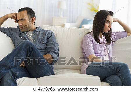 Stock Photography - Couple sitting on sofa back to back. Fotosearch