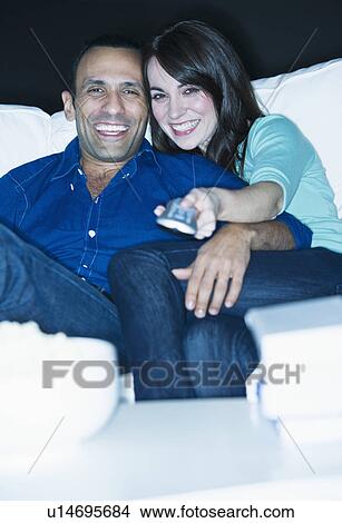 Couple watching television on sofa View Large Photo Image Picture - Couple watching television on sofa. Fotosearch