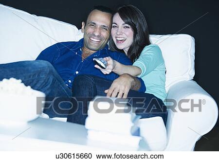 Couple watching television on sofa View Large Photo Image Stock Image - Couple watching television on sofa. Fotosearch