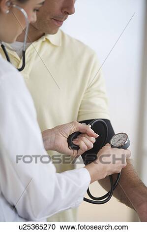 Stock Image - Doctor checking patient's blood pressure. Fotosearch