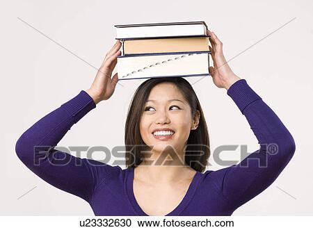 Stock Image - Female student carrying book on head. Fotosearch