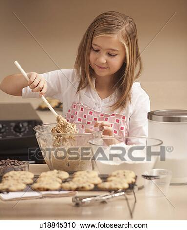 Stock Image - Girl (10-11) baking biscuits in kitchen. Fotosearch