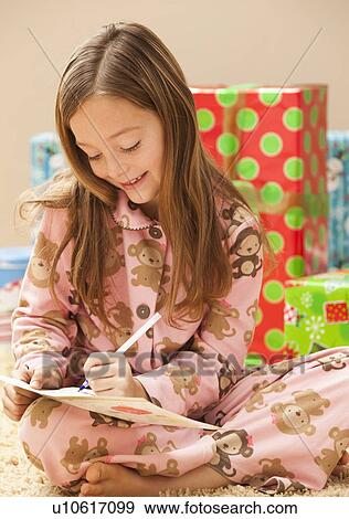 Stock Photo - Girl (6-7) preparing Christmas presents. Fotosearch