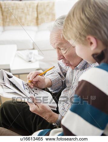 Stock Photography - Grandfather and grandson (8-9) doing crossword. Fotosearch