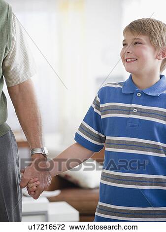 Stock Image - Grandfather and grandson (8-9) holding hands. Fotosearch