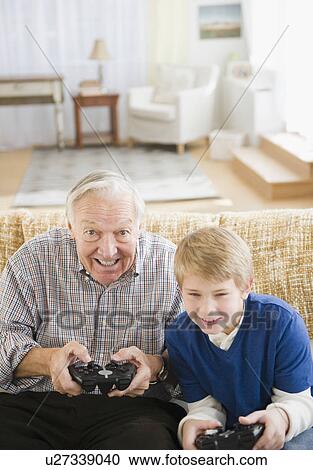 Stock Image - Grandfather and grandson (8-9) playing video games. Fotosearch