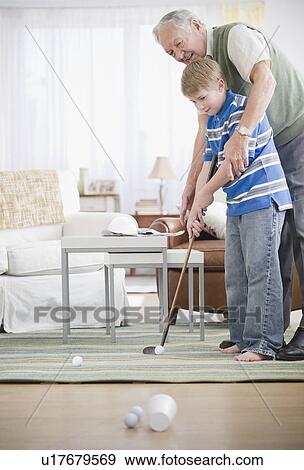 Grandfather and grandson (8-9) playing golf at home View Large Photo Image Stock Photo - Grandfather and grandson (8-9) playing golf at home. Fotosearch