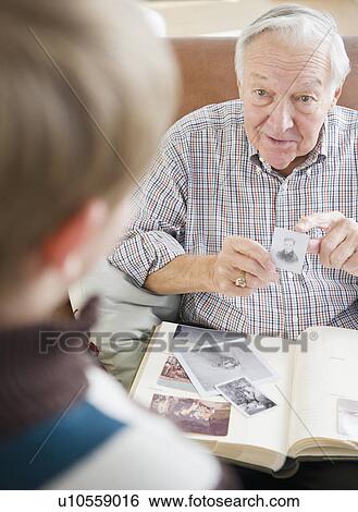 Stock Photograph - Grandfather and grandson (8-9) watching family photos. Fotosearch