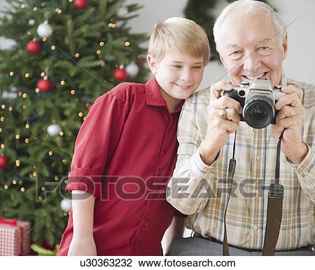 Grandfather and grandson (8-9 years) taking picture, christmas tree in background View Large Photo Image Stock Image - Grandfather and grandson (8-9 years) taking picture, christmas tree in background. Fotosearch