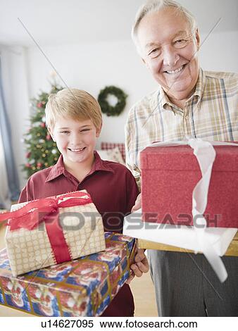 Stock Photography - Grandfather and grandson (8-9 years) holding christmas gifts. Fotosearch