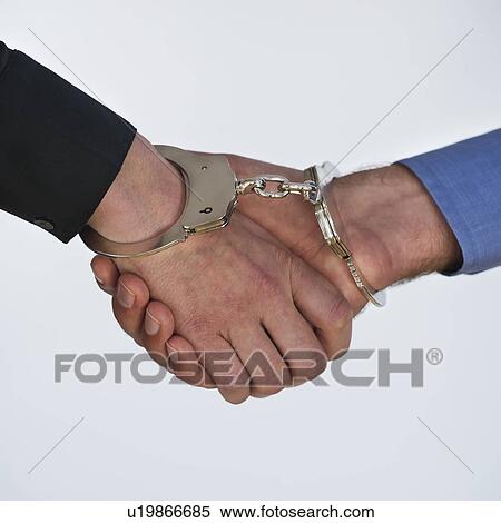 Stock Photography - Handshake with handcuffs, studio shot. Fotosearch