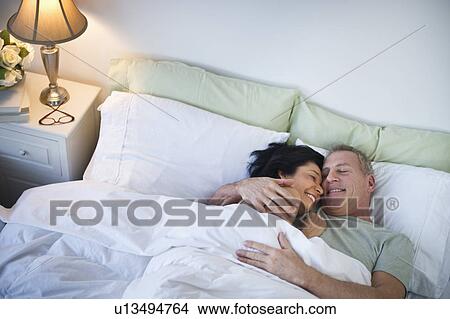 Happy mature couple laying in bed View Large Photo Image Picture - Happy mature couple laying in bed. Fotosearch