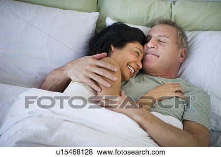 Happy mature couple laying in bed View Large Photo Image Stock Photo - Happy mature couple laying in bed. Fotosearch