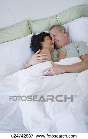 Stock Photo - Happy mature couple laying in bed. Fotosearch