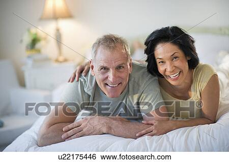 Stock Photograph - Happy mature couple laying in bed. Fotosearch
