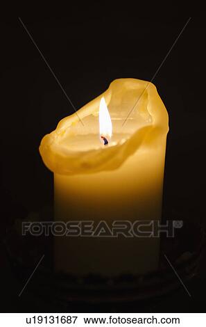 Stock Photo - Illuminated candle on black background. Fotosearch