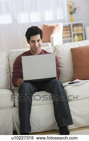 Man using laptop on sofa View Large Photo Image Stock Photo - Man using laptop on sofa. Fotosearch