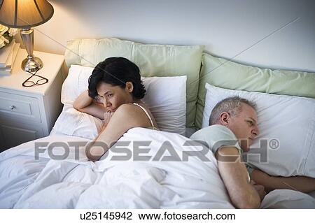 Mature couple laying in bed after argument View Large Photo Image Stock Image - Mature couple laying in bed after argument. Fotosearch