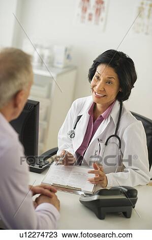 Stock Image - Mature man talking to female doctor. Fotosearch