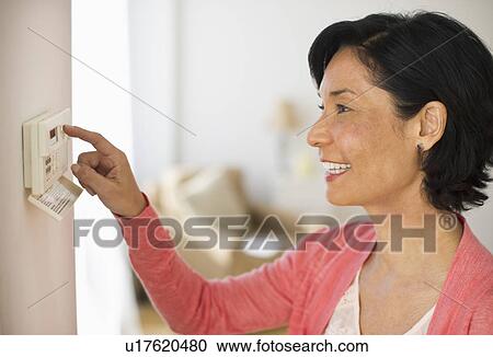Mature woman adjusting room temperature View Large Photo Image Stock Image - Mature woman adjusting room temperature. Fotosearch
