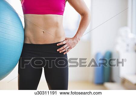 Stock Image - Midsection of woman holding fitness ball. Fotosearch