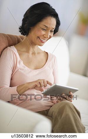 Stock Image - Mixed race woman using digital tablet. Fotosearch