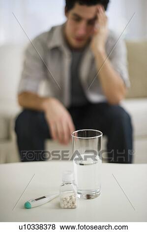 Stock Photo - Out-of-focus man taking painkillers. Fotosearch