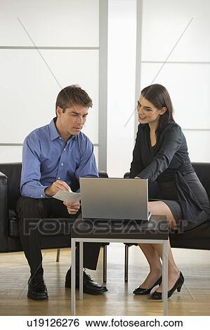 Stock Photograph - Pair of businesspeople working in office. Fotosearch