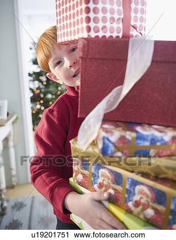 Stock Image - Portrait of boy (8-9) carrying Christmas gifts. Fotosearch