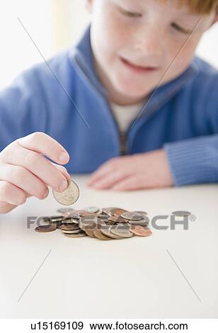 Stock Photo - Portrait of boy (8-9) counting coins. Fotosearch
