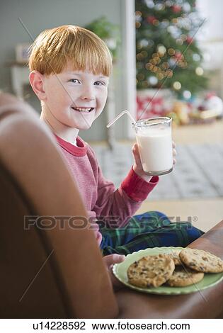 Portrait of boy (8-9) holding milk and cookies on Christmas Eve View Large Photo Image Stock Image - Portrait of boy (8-9) holding milk and cookies on Christmas Eve. Fotosearch