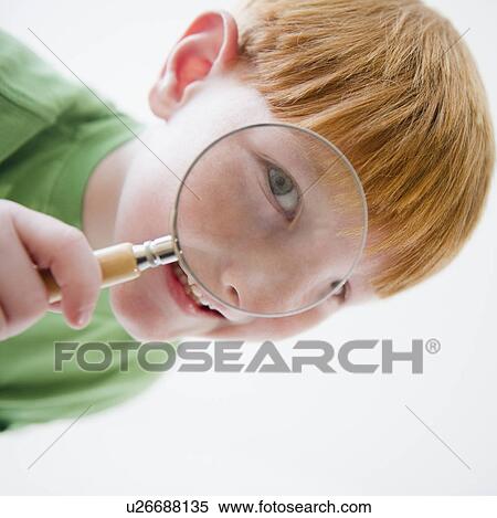 Stock Photography - Portrait of boy (8-9) looking through magnifying glass. Fotosearch