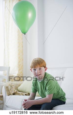 Stock Photograph - Portrait of boy (8-9) with green balloon. Fotosearch