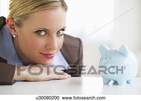 Stock Image - Portrait of businesswoman with piggy bank. Fotosearch