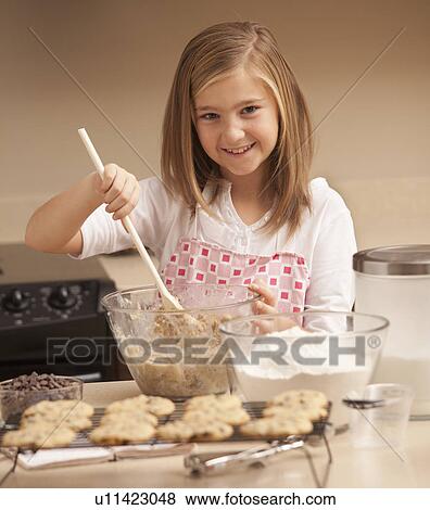 Stock Photo - Portrait of girl (10-11) baking biscuits in kitchen. Fotosearch